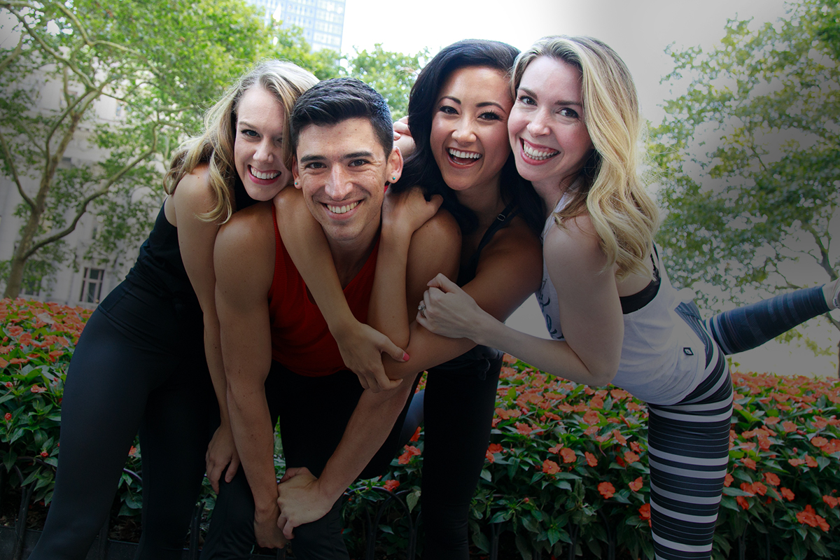 A group of Physique 57 barre instructors arm-in-arm smiling at the camera.